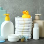 Natural and reusable baby products including cloth diapers, glass bottles, and organic cotton clothes displayed neatly on a baby mat.
